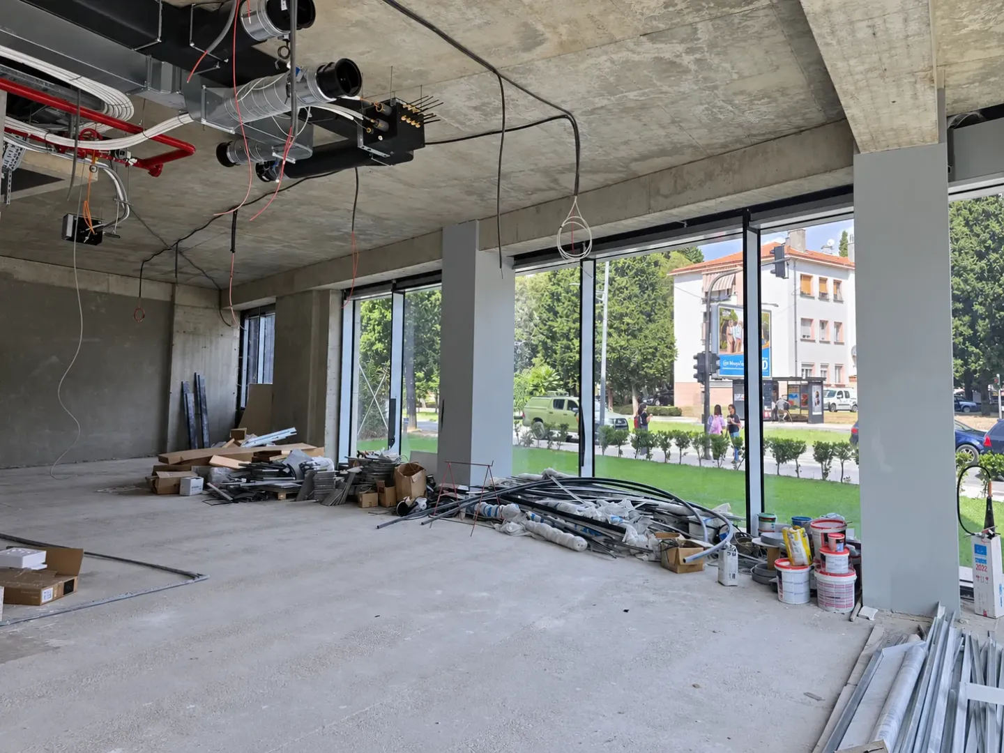 Unfinished commercial space under construction with large windows and ceiling installations.