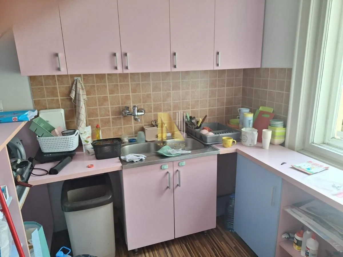 Small kitchen with a sink, countertop, and pink wall cabinets.