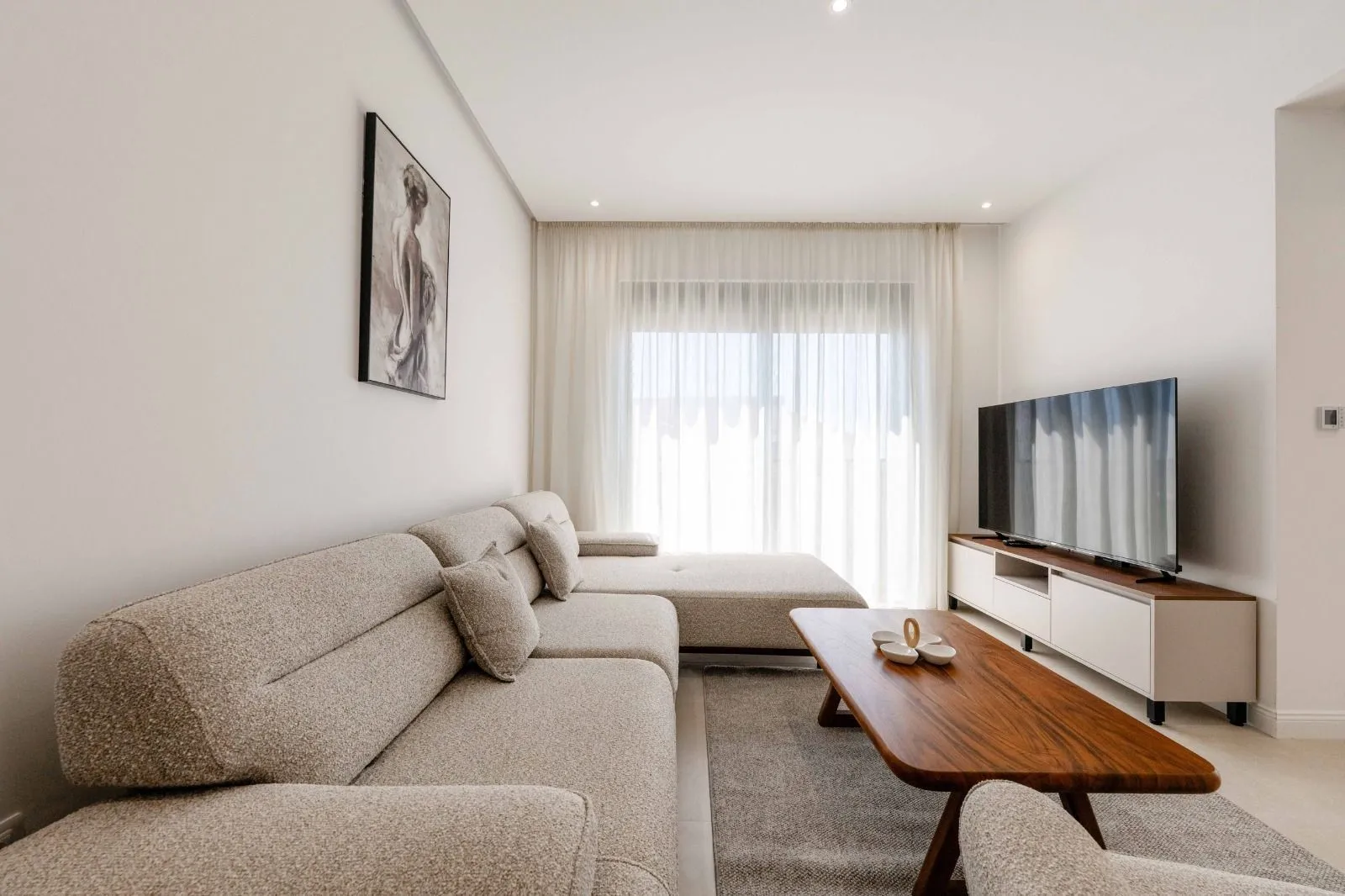Modern and bright living room with a sectional sofa and a TV.