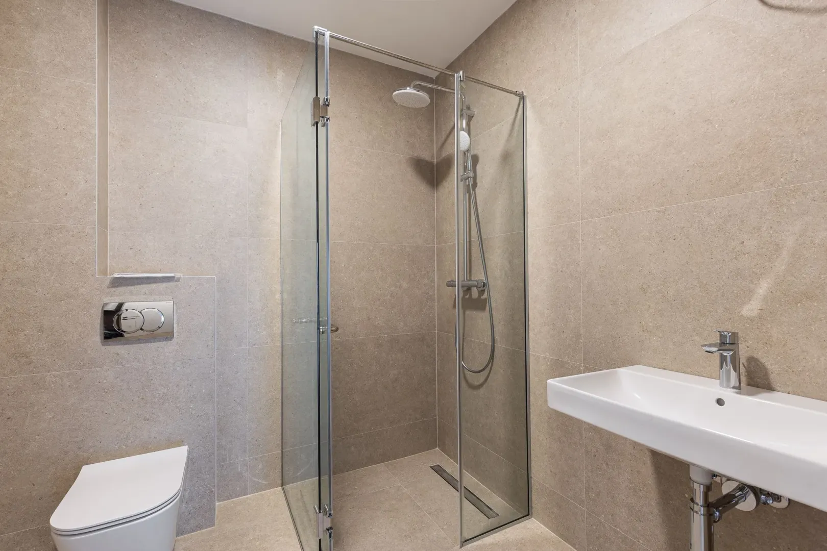 Modernly equipped bathroom with a walk-in shower, washbasin, and wall-mounted toilet.