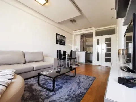 Spacious living room with a sofa, coffee table, and a view of the dining area and kitchen. - image 2