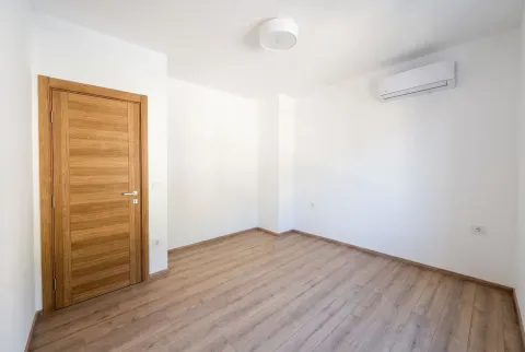 Empty room with white walls, wooden flooring, and an air conditioning unit. - image 5