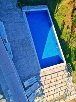 Pogled odozgo na otvoreni bazen sa popločanim platoom i ležaljkama. - image 2