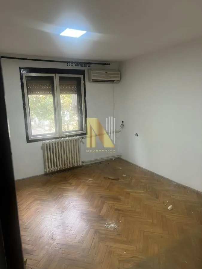 Prazna soba sa parketom i prozorom.