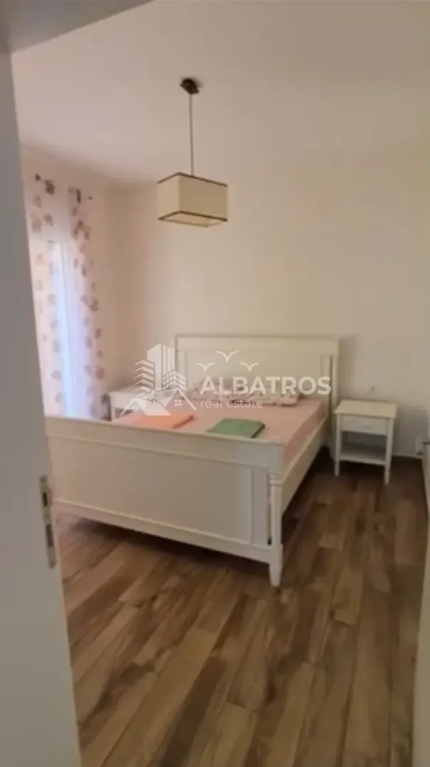 Spavaća soba sa bračnim krevetom i noćnim stočićima.