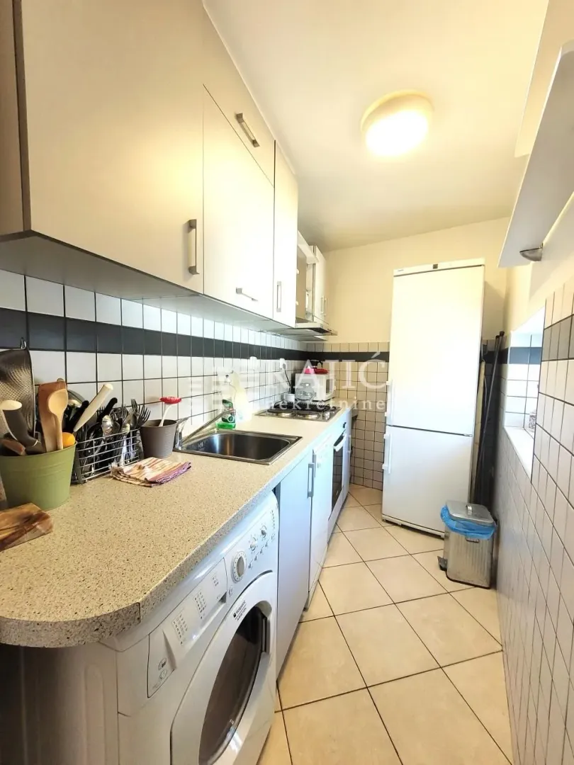 Smaller white kitchen with cabinets and built-in appliances.