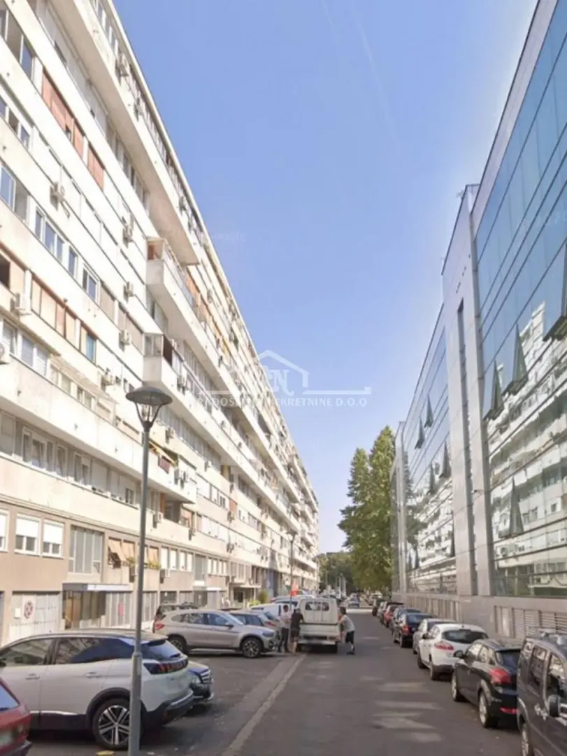 Pogled na ulicu i zgrade sa parkingom ispred objekta.