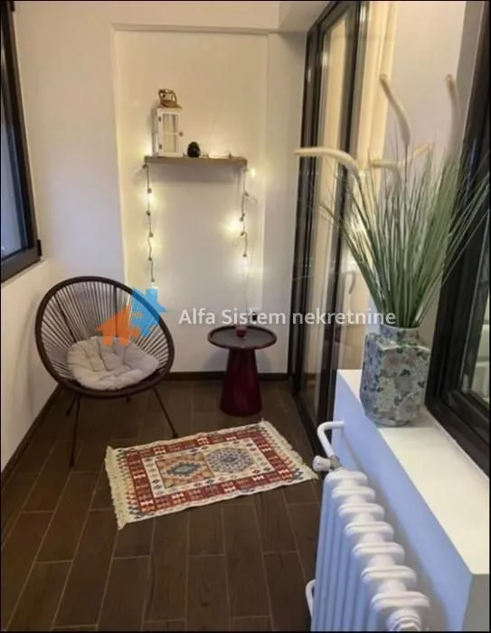 Enclosed balcony furnished with a chair, small table, and decorative items.