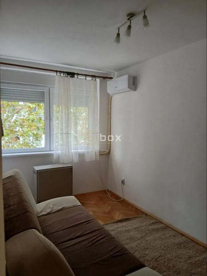 Manja dnevna soba sa kaučem, klima-uređajem i prozorom.