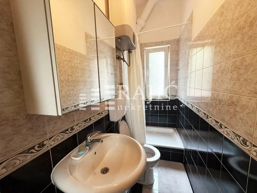Small tiled bathroom with a sink, toilet, and shower enclosure.