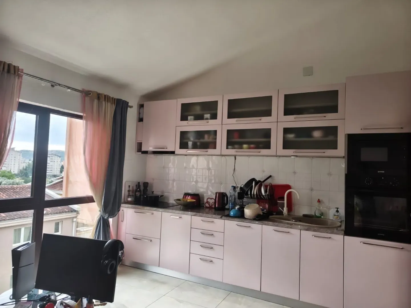 Manja kuhinja sa roze elementima i ugradnom rernom.