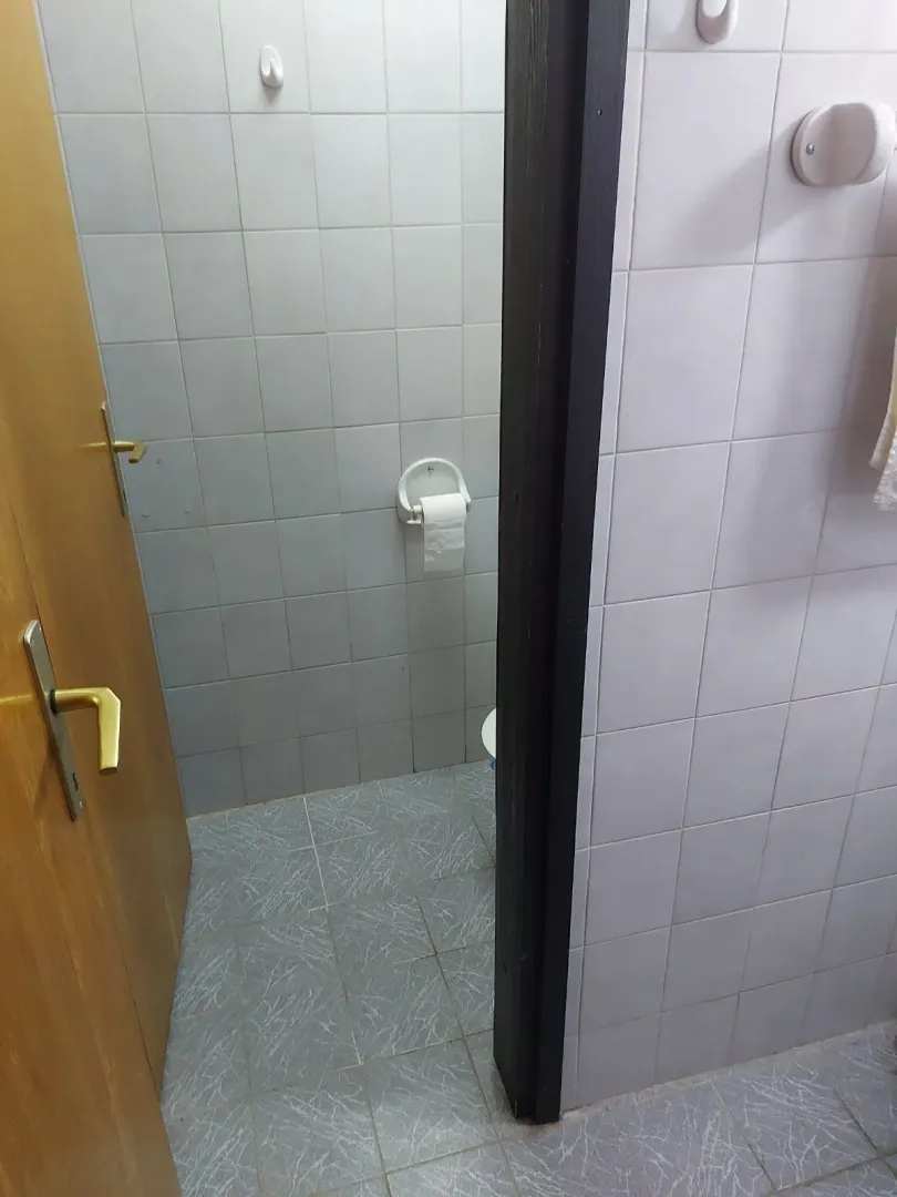 A view through an open doorway into a bathroom with white tiled walls.