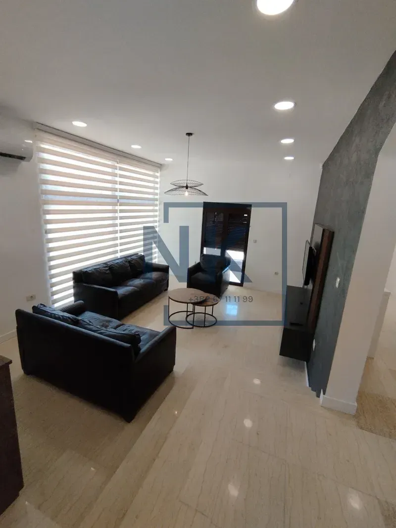 Living room with black sofas and a TV unit.