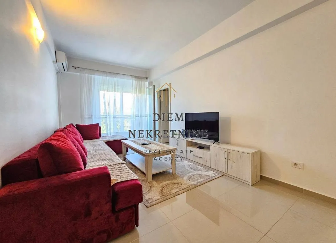 Living room with a red sectional sofa, TV unit, and bright walls.