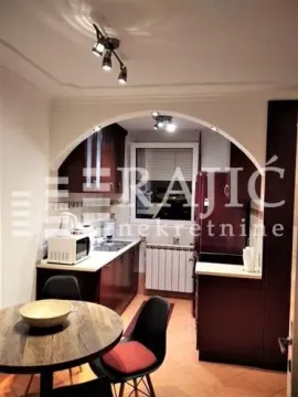 Dining area with a view of a smaller kitchen in the background. - image 6