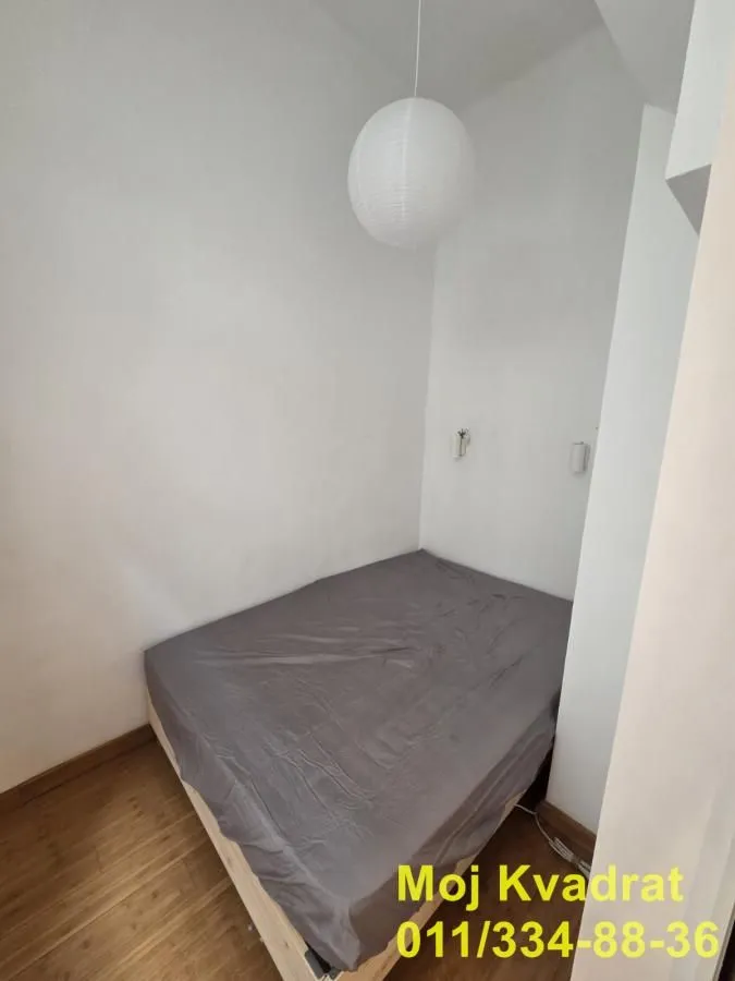 Manja spavaća soba sa krevetom i belim zidovima.