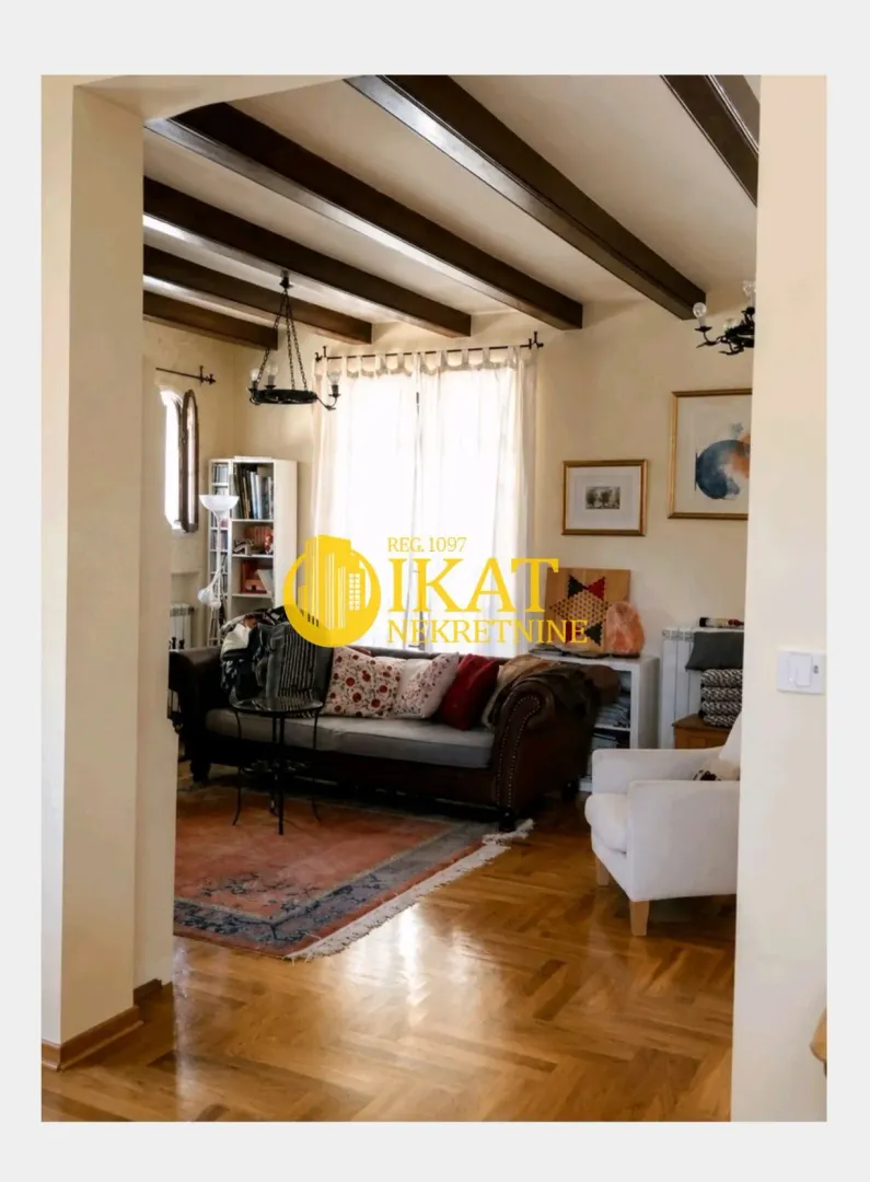 Living room with a sofa, parquet flooring, and wooden ceiling beams.