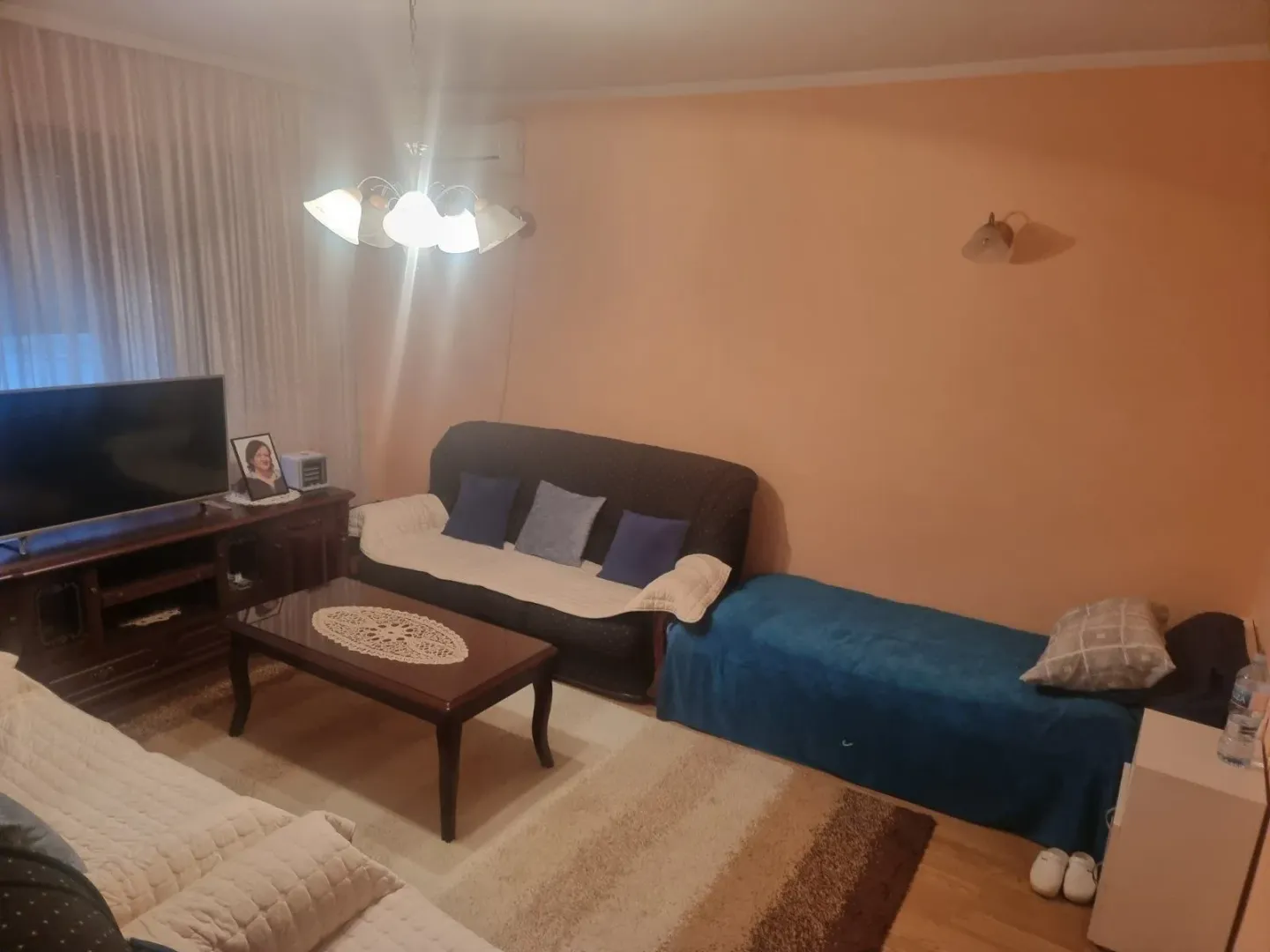 Dnevna soba sa garniturom za sedenje, stočićem i televizorom.