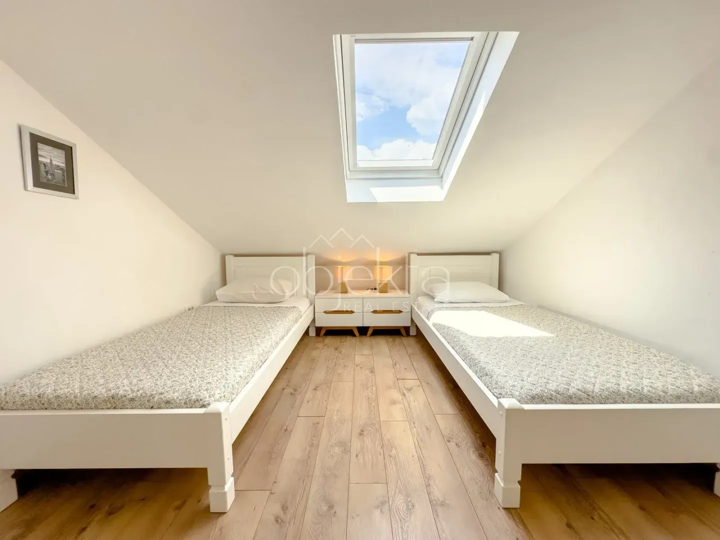 Attic bedroom furnished with two single beds and a skylight.
