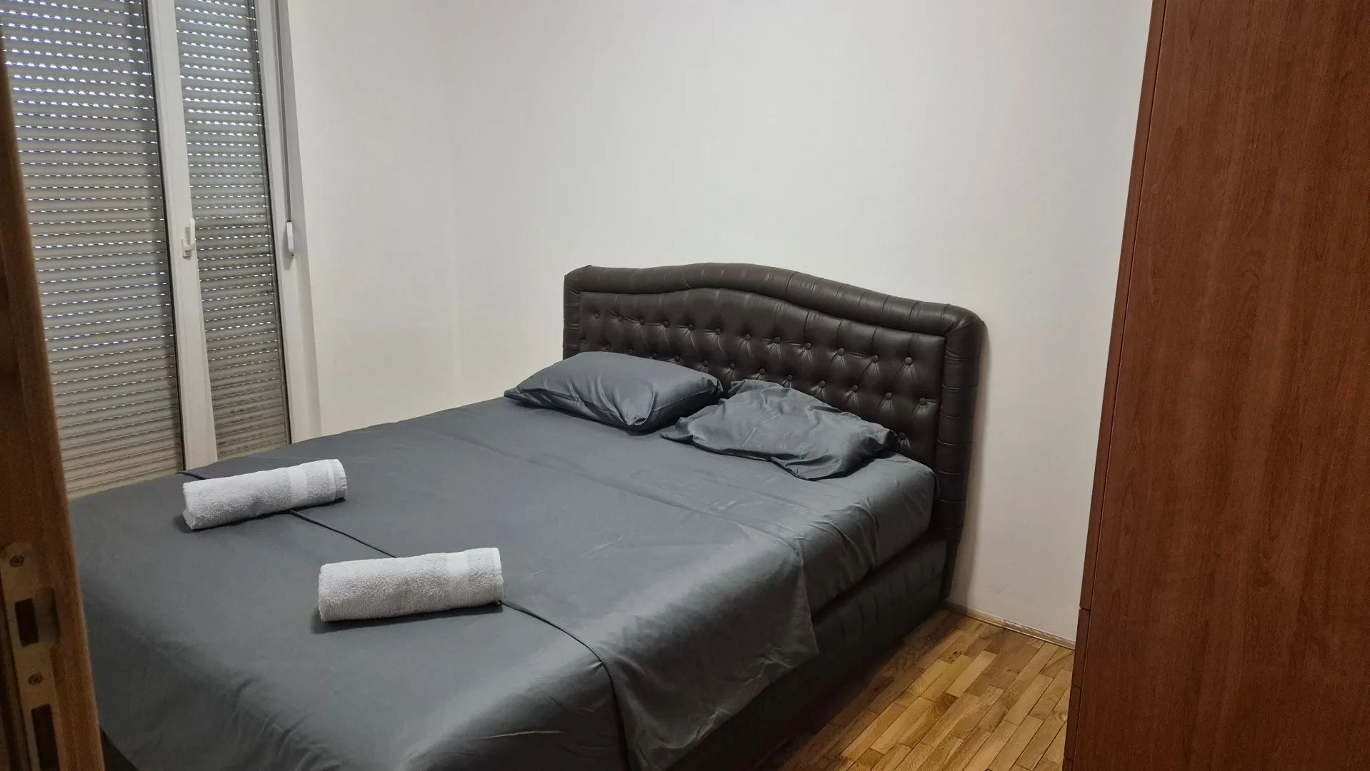 Bedroom with a double bed, wooden flooring, and balcony doors.