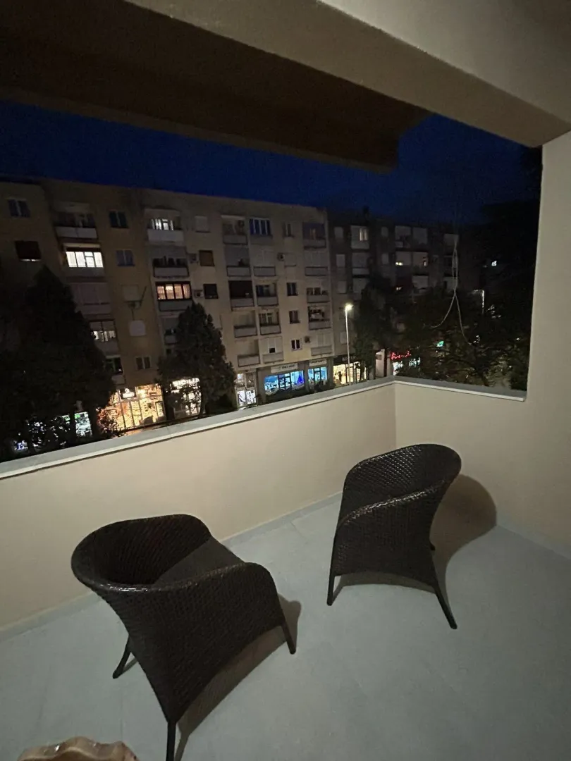 Balcony with two armchairs and a city view.