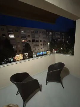 Balcony with two armchairs and a city view. - image 10