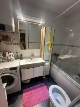 Bathroom equipped with a washbasin, bathtub, toilet, and washing machine. - image 18