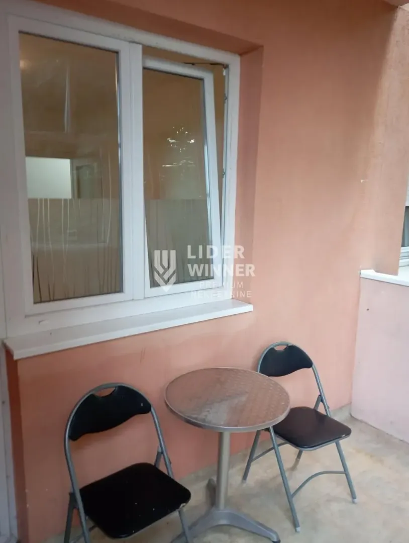 Manji balkon sa stolom i dve stolice pored prozora.