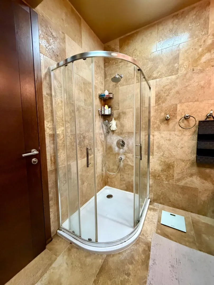Bathroom with a shower cabin tiled in beige tiles.