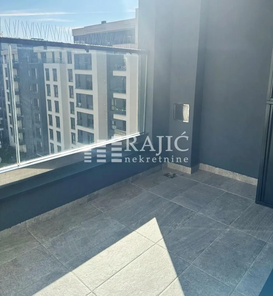 Modern terrace with tiles and a glass railing.