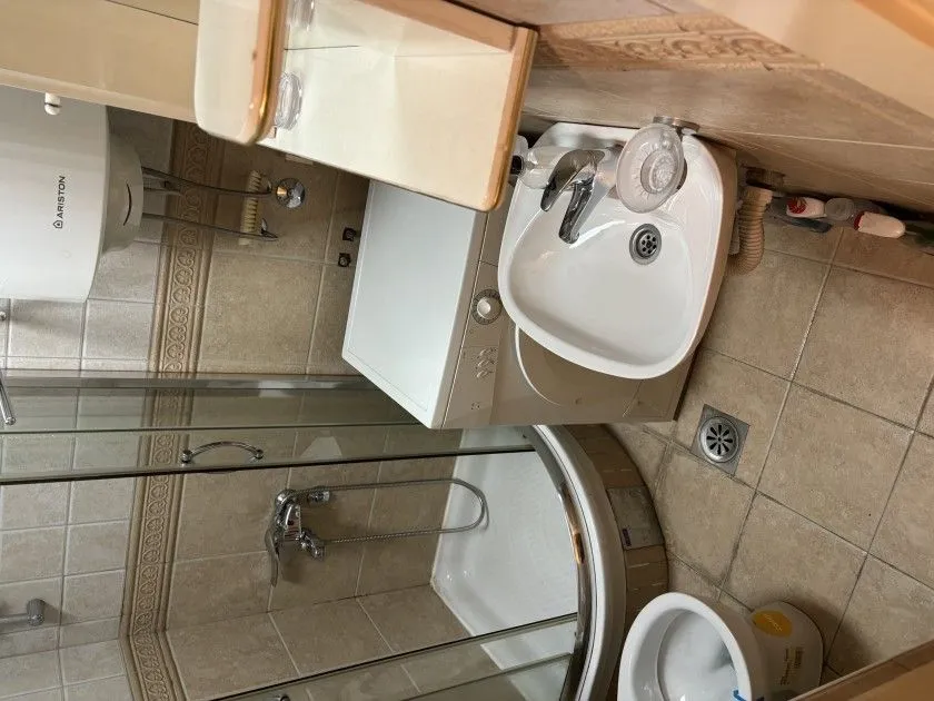 Manje kupatilo sa tuš kabinom, lavaboom i veš mašinom.