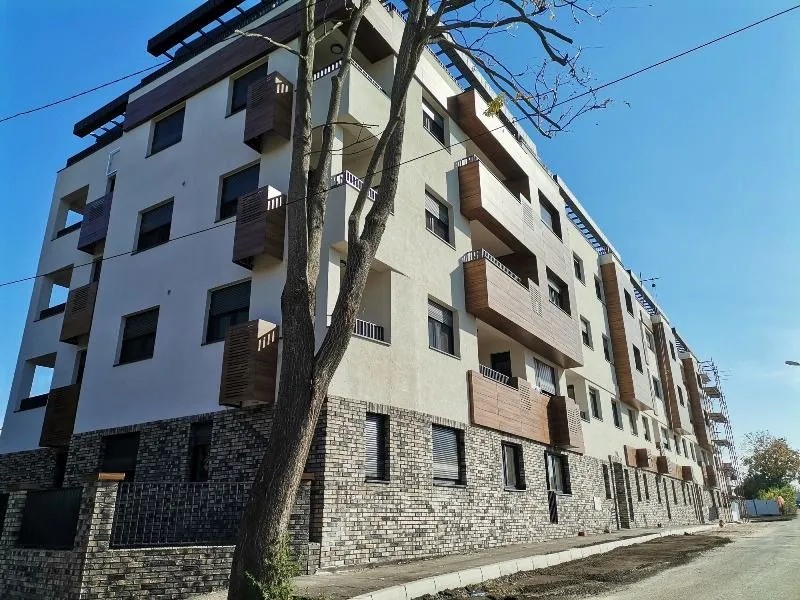 Spoljašnji izgled moderne stambene zgrade sa balkonima i uređenom fasadom.