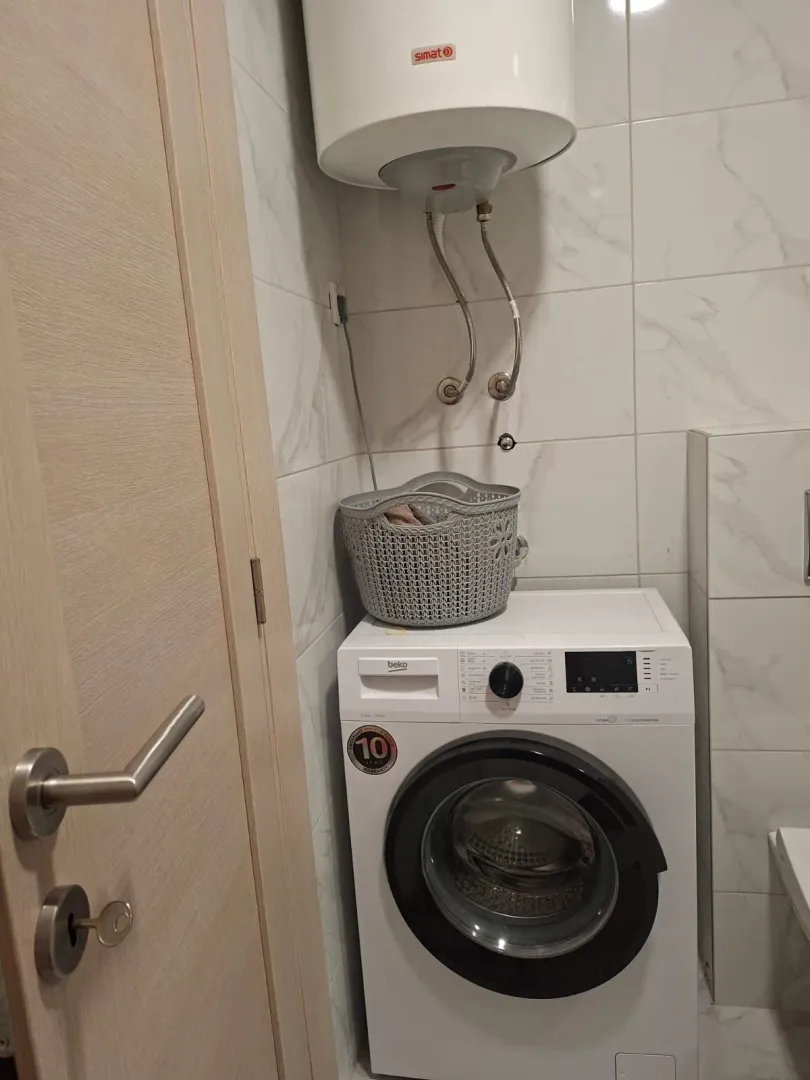 Kupatilo sa veš mašinom, bojlerom i korpom za veš.