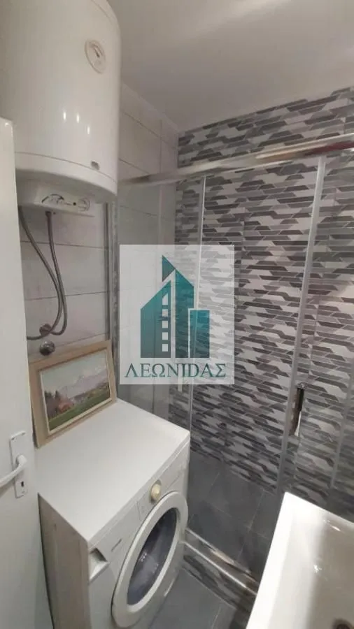 Bathroom with a shower cabin, water heater, and washing machine.