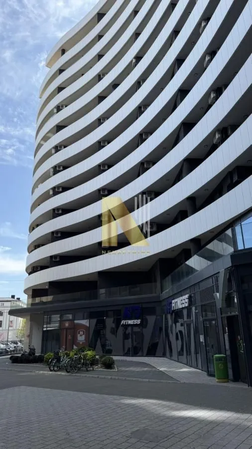 Eksterijer moderne stambene zgrade sa terasama i poslovnim prostorom u prizemlju.