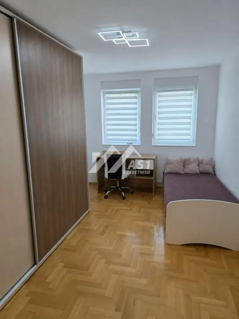 Smaller bedroom with a bed, desk, and a large wardrobe.