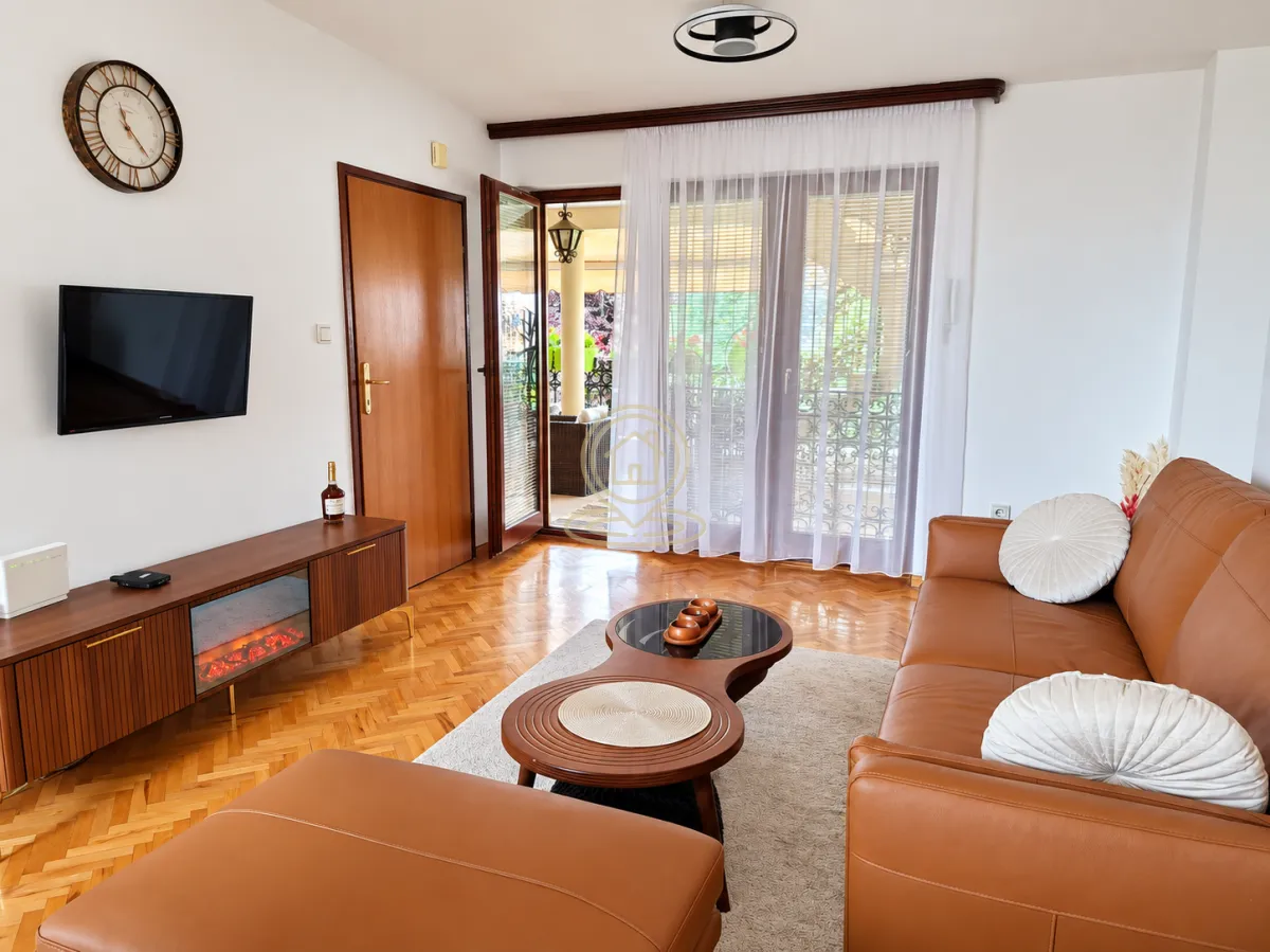 Living room with leather sofa set, TV, and access to the terrace.