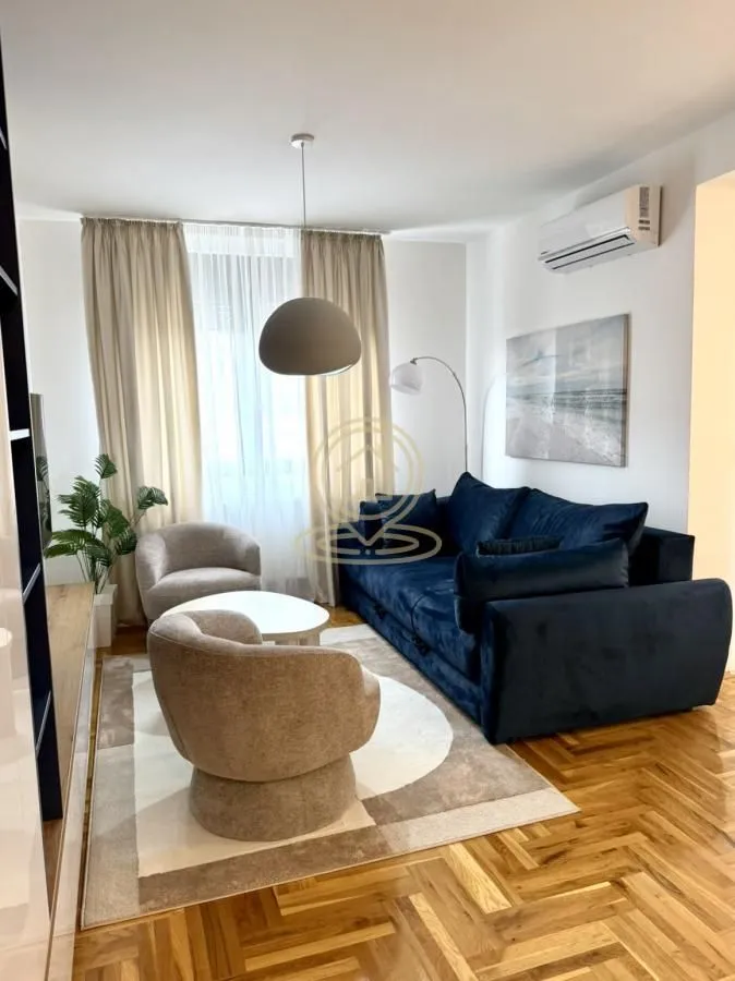 Living room with a blue sofa, armchairs, and hardwood floors.