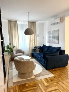 Living room with a blue sofa, armchairs, and hardwood floors. - image 2