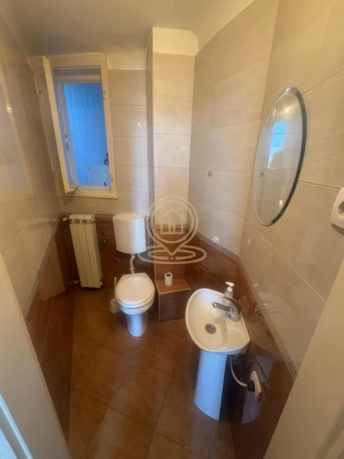 Small bathroom with a sink, toilet, and window.