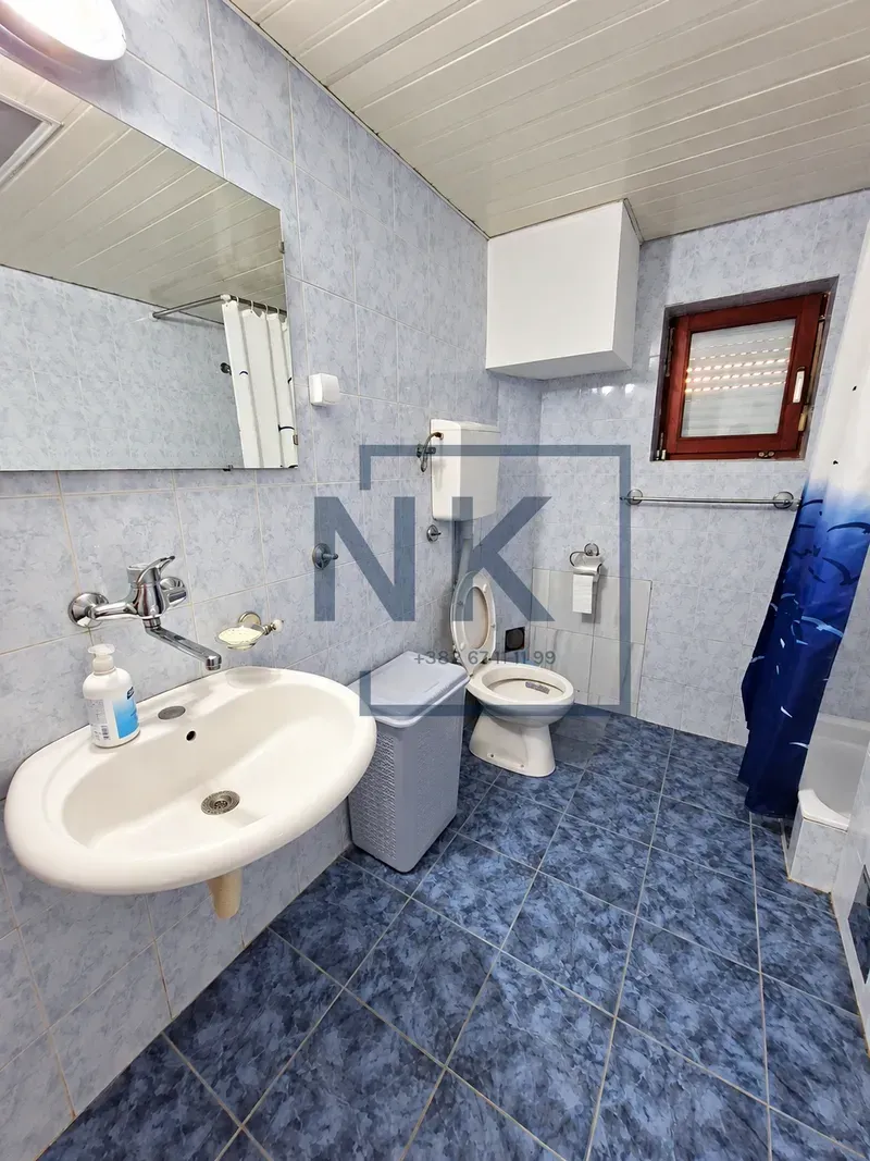 Tiled bathroom with a washbasin, toilet, and bathtub.