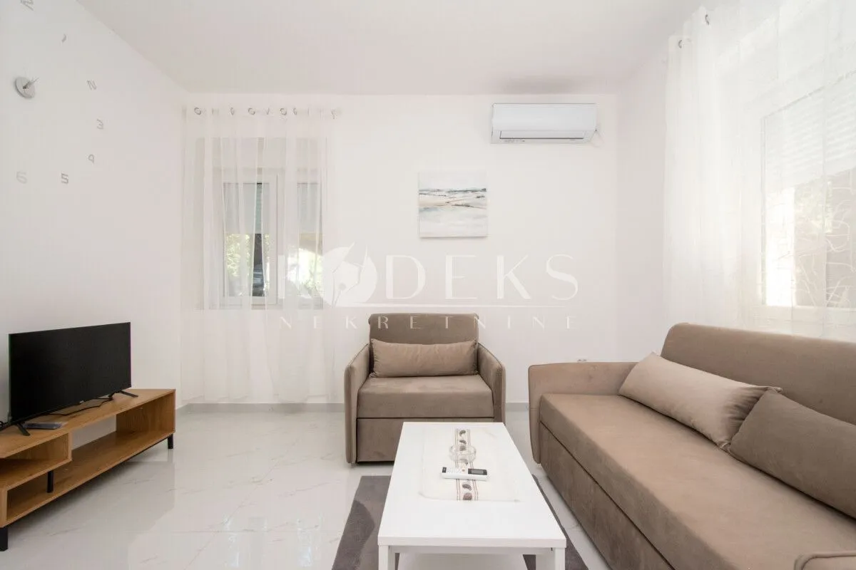 Living room with a sofa, TV, and air conditioning unit.