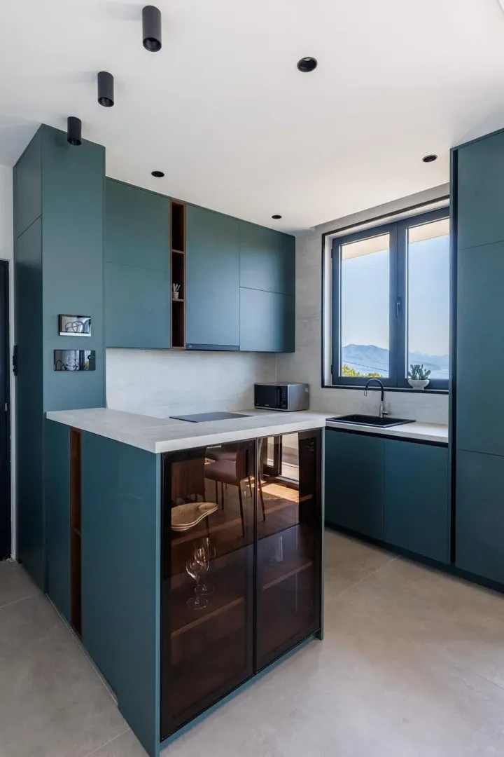Modern kitchen with dark green cabinetry and a sea view.