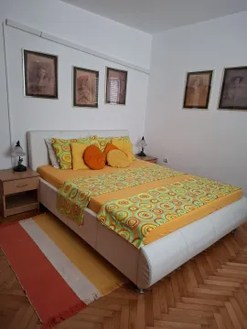 Namještena spavaća soba sa bračnim krevetom, noćnim stolićima i slikama na zidu. - image 15