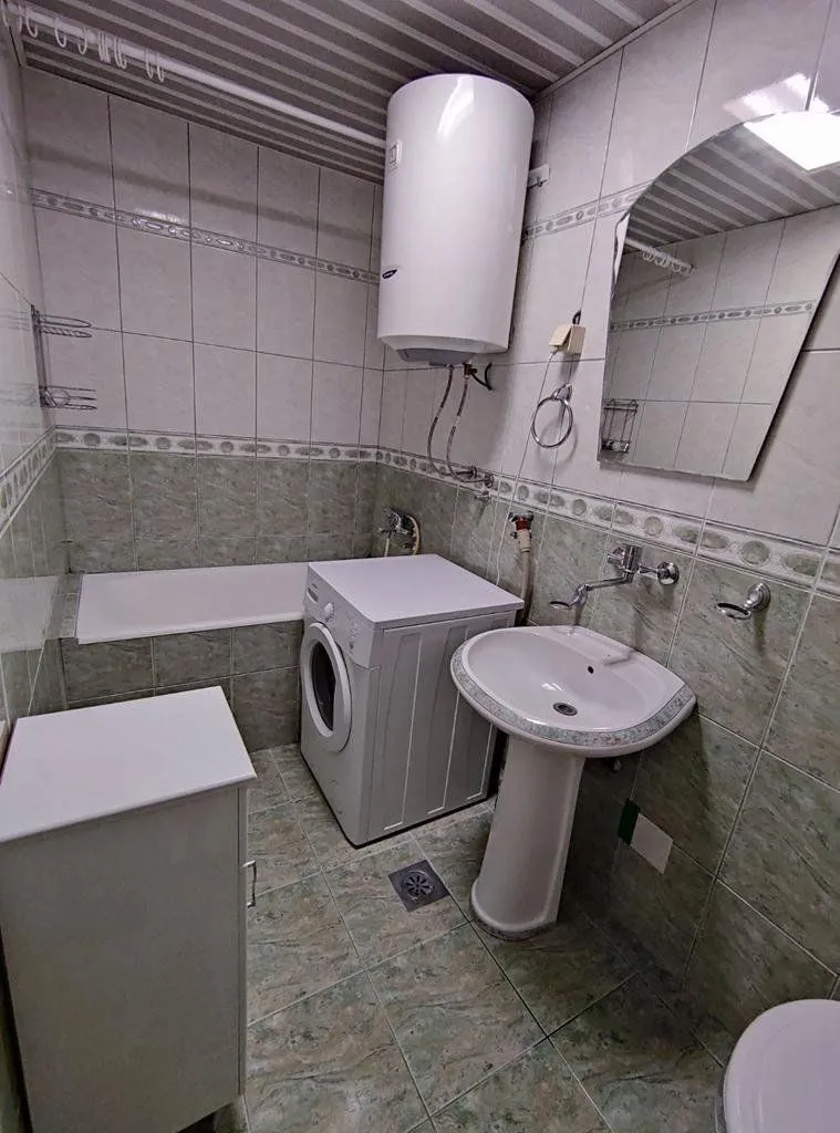Bathroom equipped with a bathtub, washbasin, washing machine and water heater.