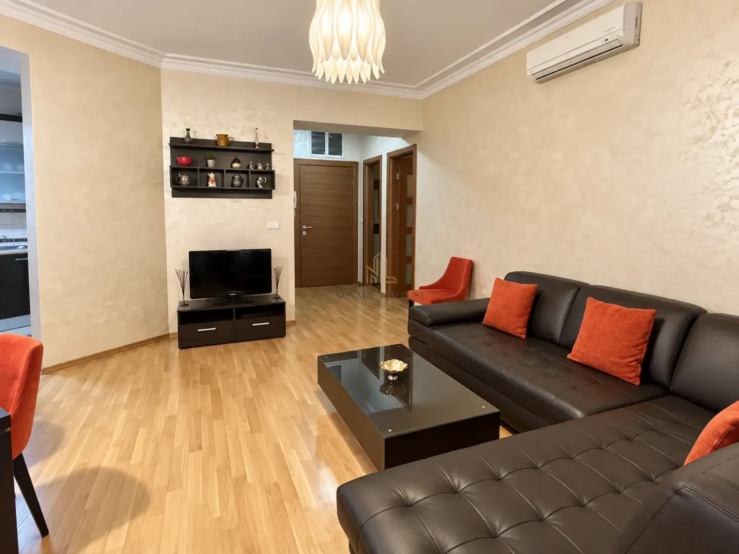 Living room with a black leather sofa, TV, and dining area.