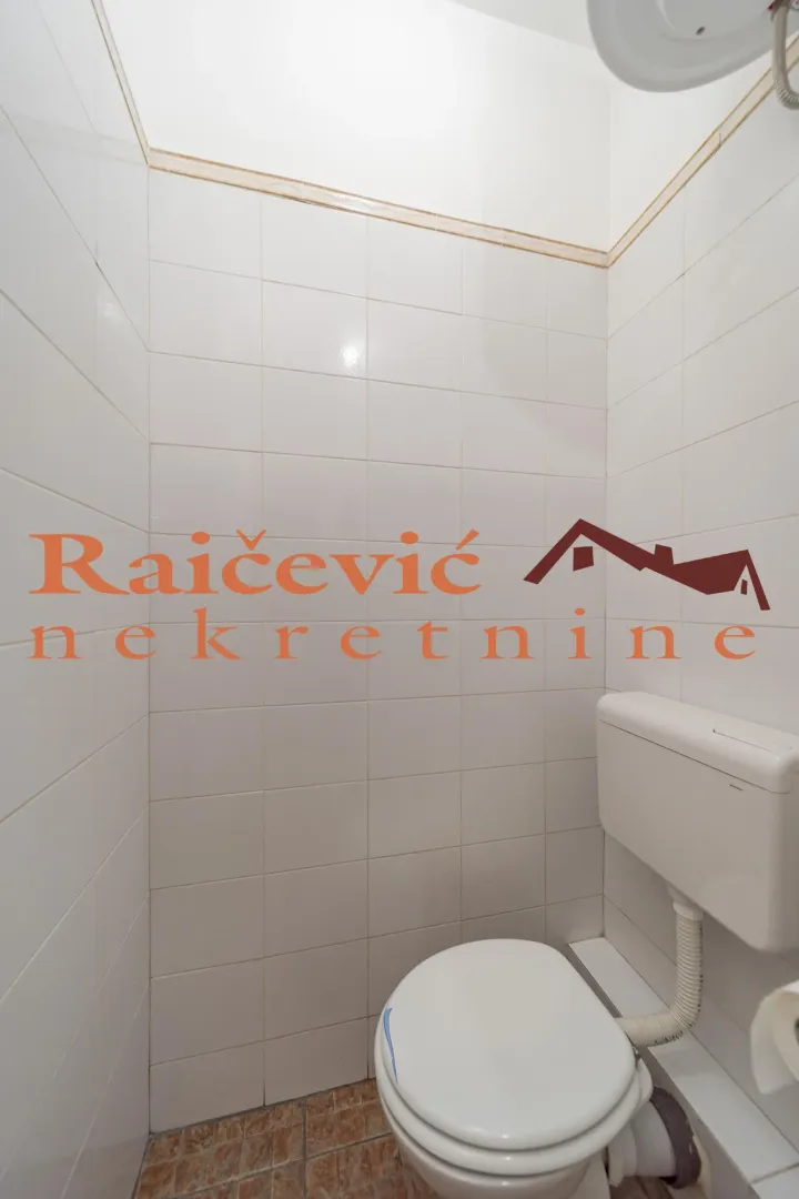 Smaller bathroom tiled with white tiles featuring a toilet bowl and cistern.