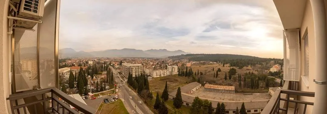 Pogled sa terase na panoramu grada i planine u daljini.