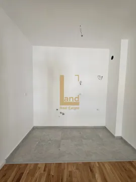 Prazna prostorija sa bijelim zidovima, sivim pločicama i drvenim podom. - image 3
