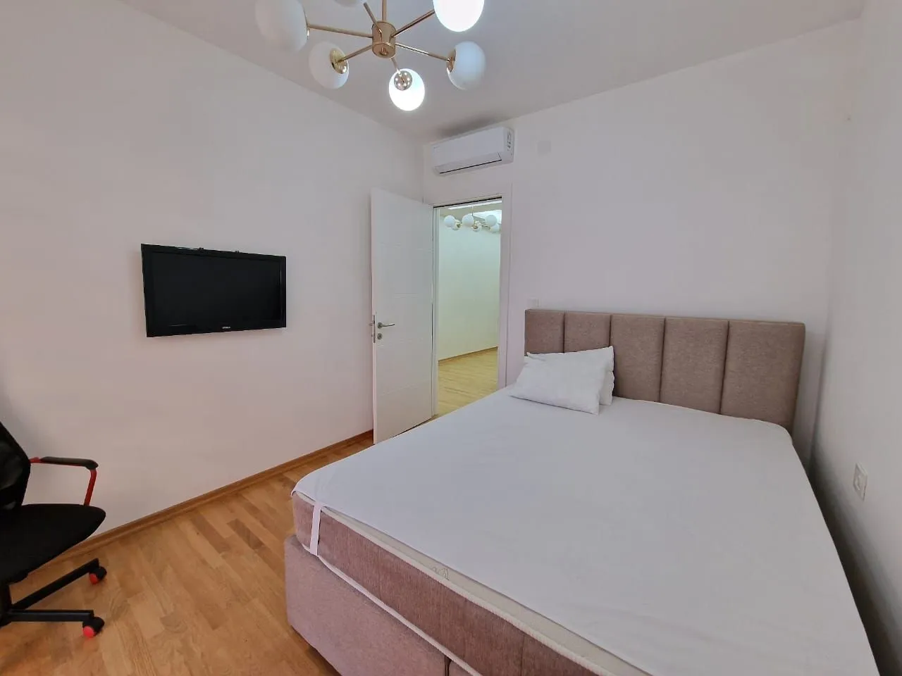 Furnished bedroom with a double bed, television, and air conditioning.